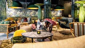 Ein modernes Interieur mit einem runden Tisch, bunten Stühlen und grünen Pendelleuchten.