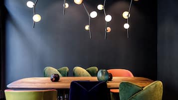 Ein Essbereich mit einem Holztisch, grünen und orangefarbenen Stühlen und einer modernen Pendelleuchte.