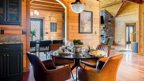A wooden interior with a dining area, a stone fireplace, and a large arched doorway. - Shenandoah Mansion (Elkton)