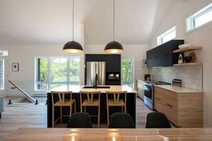 A modern kitchen with a central island, pendant lighting, and a view of the outdoors.