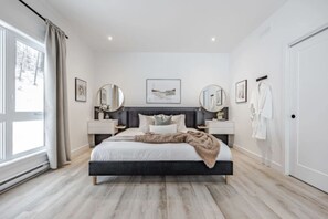 A modern bedroom with a large bed, bedside tables, a wardrobe, and a window with curtains.