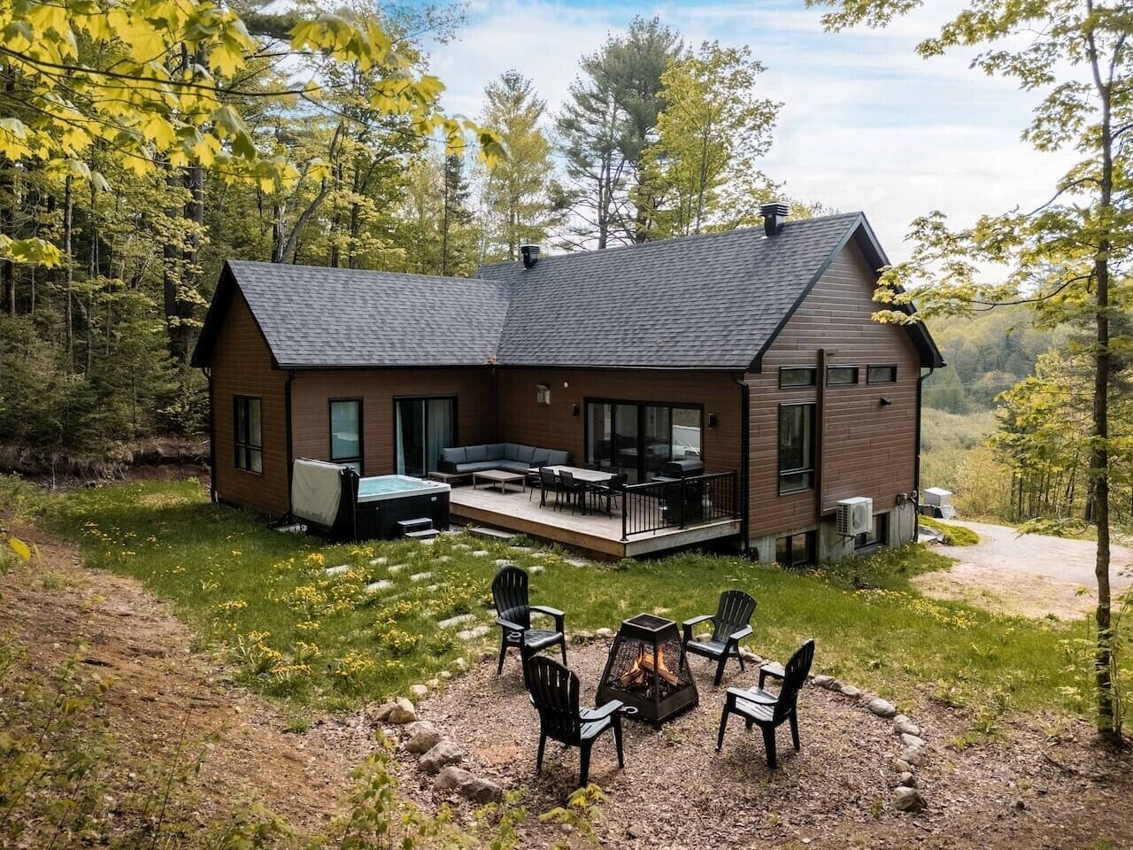 A modern house with a deck, outdoor seating, and a fire pit.