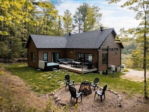 A modern house with a deck, outdoor seating, and a fire pit.