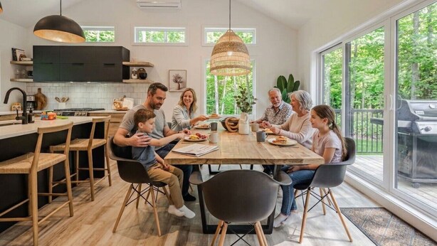 Une cuisine moderne avec un coin repas, de grandes fenêtres et une vue sur l’extérieur.
