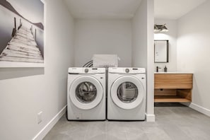 Een wasserette met twee voorladers, een houten kast en een lijst met een afbeelding aan de muur.