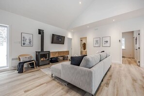 Uma sala de estar moderna com lareira, um sofá e uma TV fixada na parede.