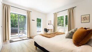 Une chambre moderne avec un grand lit, un bureau et une vue sur l’extérieur.