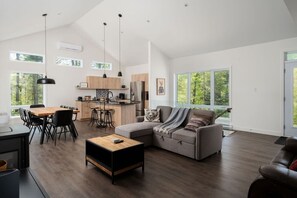 A spacious living area with a dining table, a sofa, and a kitchen in the background.