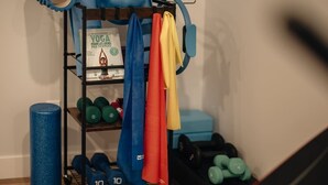 Ein Heimfitnessraum mit Trainingsgeräten, Yogamatten und Kurzhanteln.