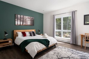 A bedroom with a large bed, a nightstand, a bedside table, a window with curtains, and a painting on the wall. - Private Hot Tub | Hiking | Skiing | Roitelet (Argenteuil Regional County Municipality)