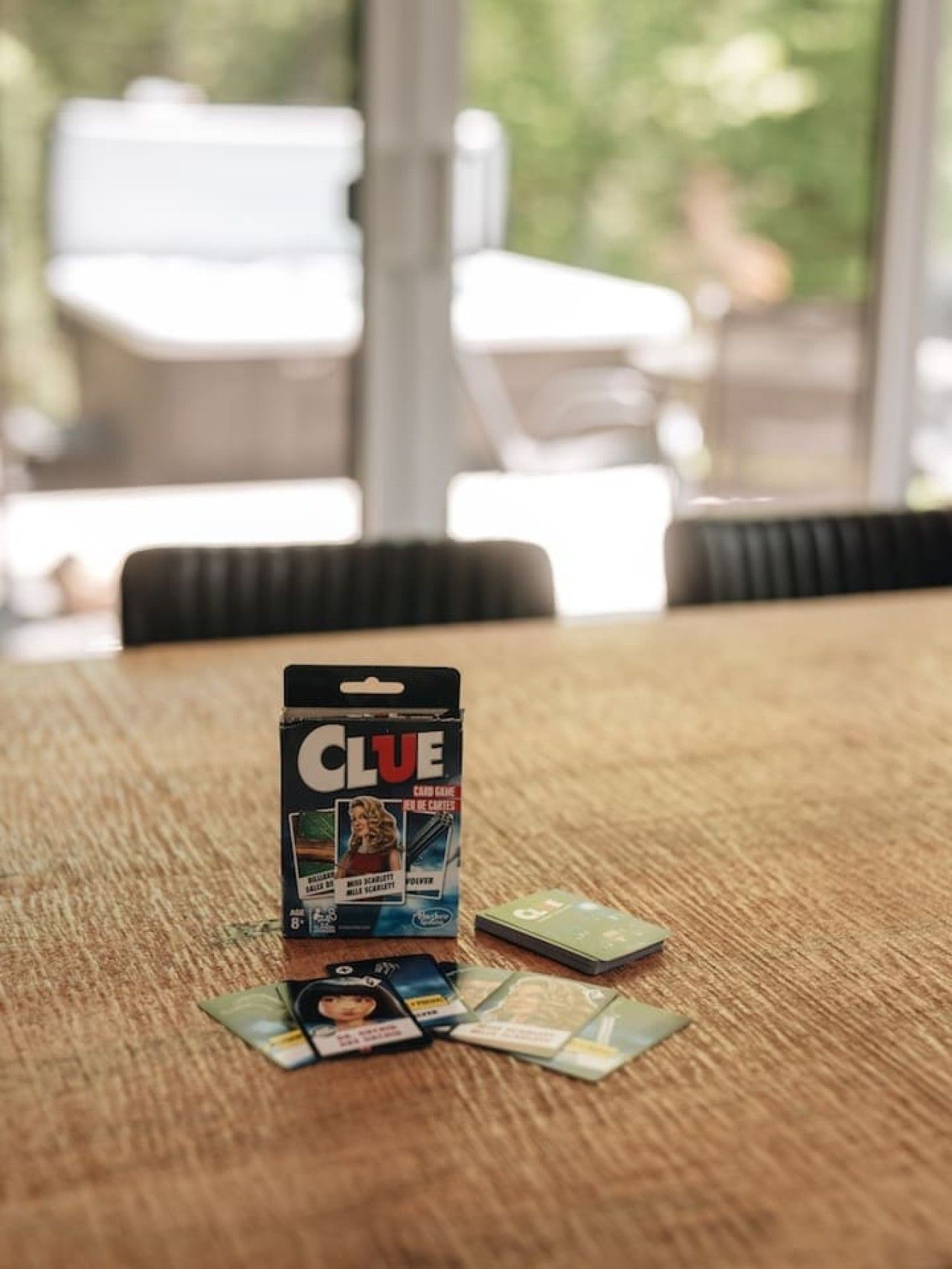 Une table sur laquelle se trouvent une boîte de jeu Cluedo et des cartes, le tout posé sur une surface en bois.