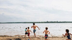 A beach scene with a group of people running towards the water. - Private Spa| Hiking| Skiing| Mini Chalet| Assinie (Brownsburg)