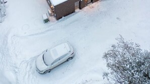 A snow-covered building with a flat roof, a car parked in front, and a forested area in the background. - Private Spa| Hiking| Skiing| Mini Chalet| Assinie (Brownsburg)