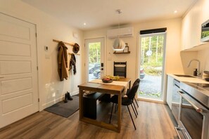 Une cuisine moderne avec un coin repas, un porte-manteau et une vue sur l’extérieur.