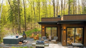 A modern outdoor living area with a hot tub, grill, and seating.