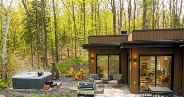 Ein moderner Außenbereich mit Whirlpool, Grill und Sitzgelegenheiten.