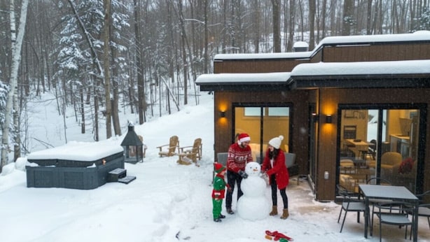 A snow-covered outdoor area with a hot tub, wooden deck, and a building with large windows. - Private Spa| Hiking| Skiing| Mini Chalet| Assinie (Brownsburg)