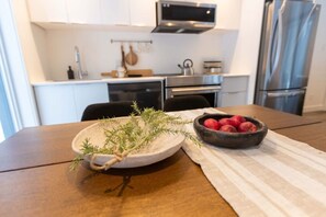 Une cuisine avec des meubles blancs, un four à micro-ondes, un four et un réfrigérateur.