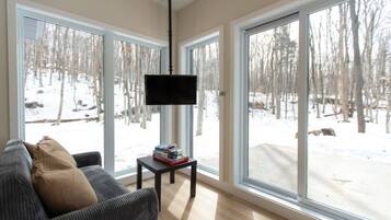 A living room with a large window, a flat-screen TV, a sofa, and a small table with books.