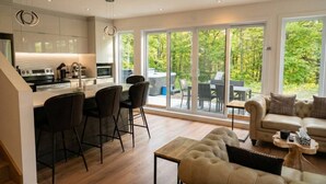 A modern kitchen with a dining area, large sliding glass doors, and a cozy seating area with a sofa and coffee table.