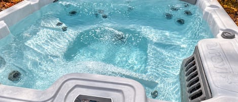 A hot tub with a control panel, surrounded by trees.