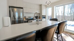 A modern kitchen with a large island, stainless steel appliances, and a view of the outdoors.