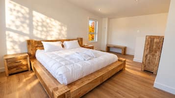 A bedroom with a wooden bed frame, a bedside table, a bench, and a wardrobe.