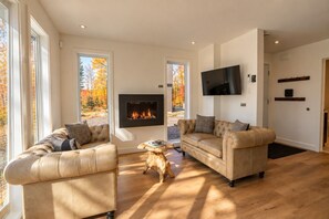 A modern living room with two leather sofas, a fireplace, and a television mounted on the wall.