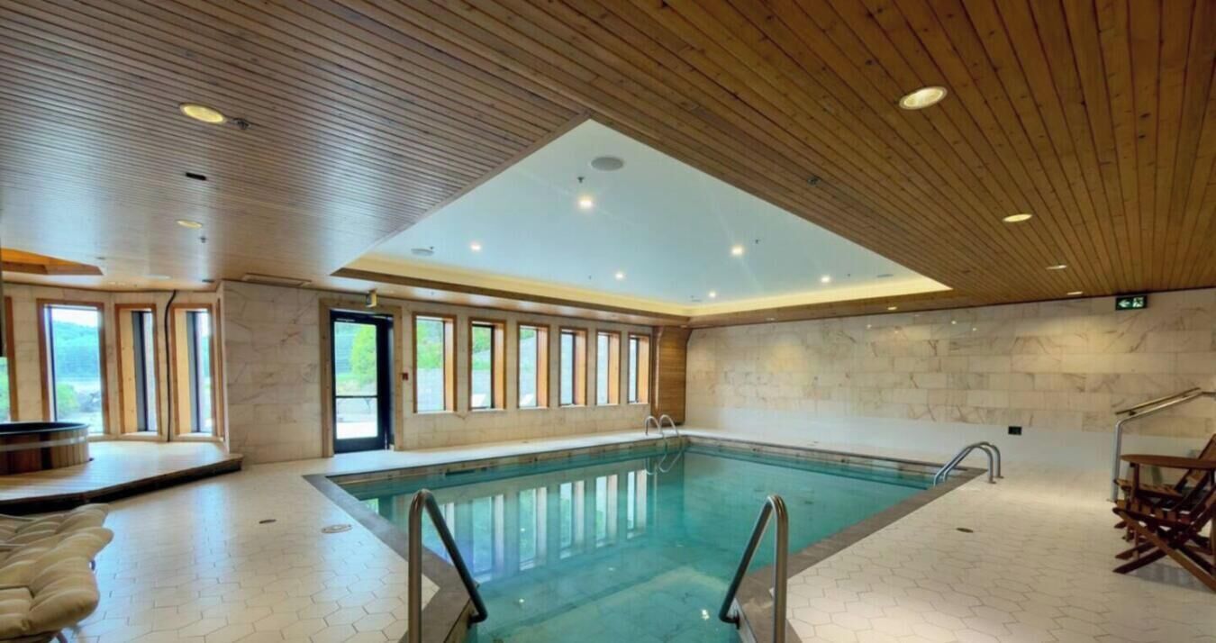 An indoor swimming pool with a high ceiling and large windows.