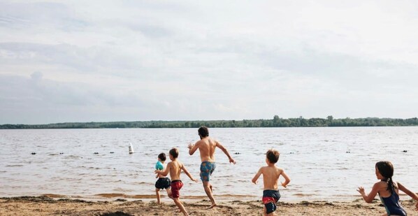 Una spiaggia con un gruppo di persone che corrono verso l'acqua.