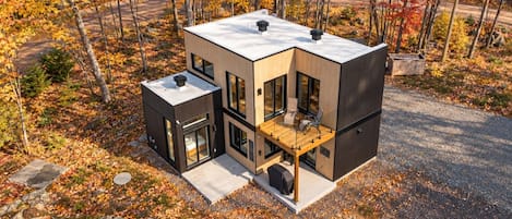 Une maison moderne à deux étages, dotée d’un balcon, de grandes fenêtres et d’un garage.