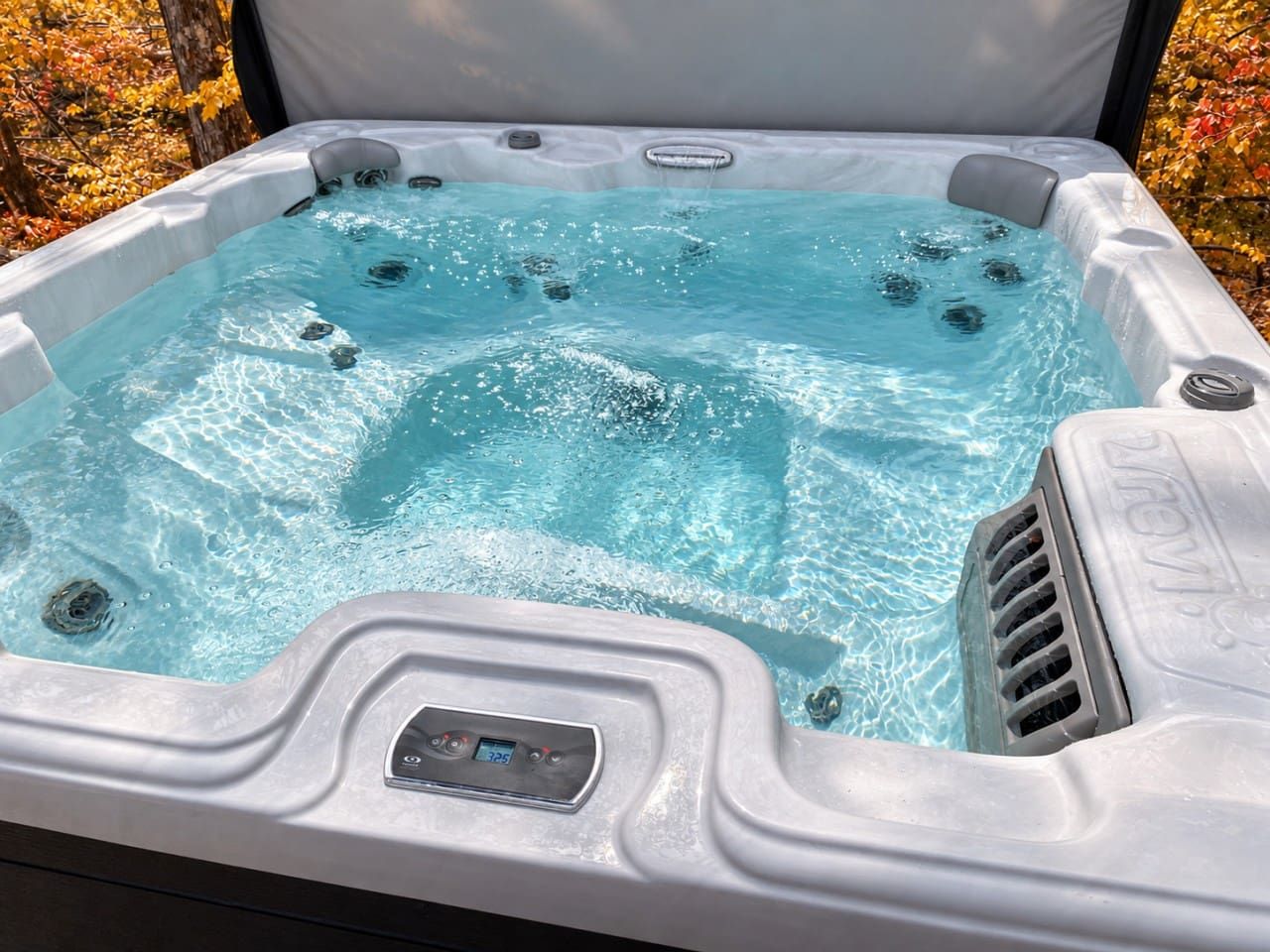 Un jacuzzi con panel de control y chorros, rodeado de árboles.