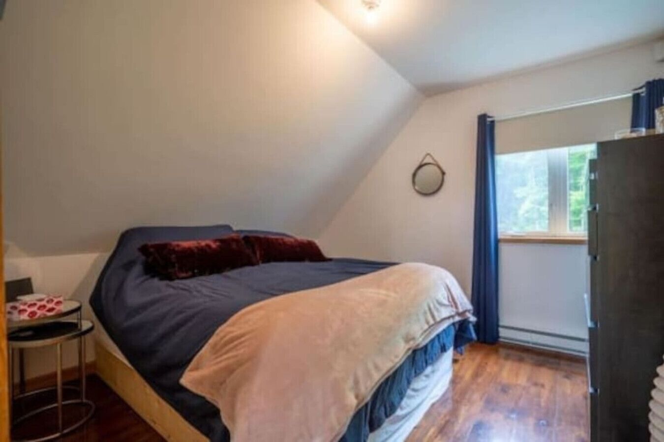 Une petite chambre à coucher, chaleureuse et accueillante, avec un lit simple, une petite table et une fenêtre avec des rideaux.