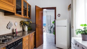 A kitchen with wooden cabinets, a gas stove, a refrigerator, and a washing machine. - La Casa Dell Isola by Wonderful Italy (Syracuse)