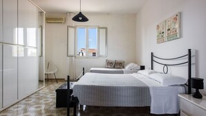 A bedroom with two beds, a chair, a desk, and a window with a view. - La Casa Dell Isola by Wonderful Italy (Syracuse)