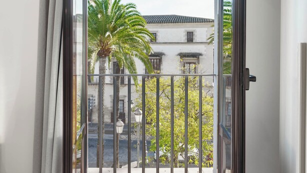 Un balcón abierto con vistas a un edificio y palmeras.