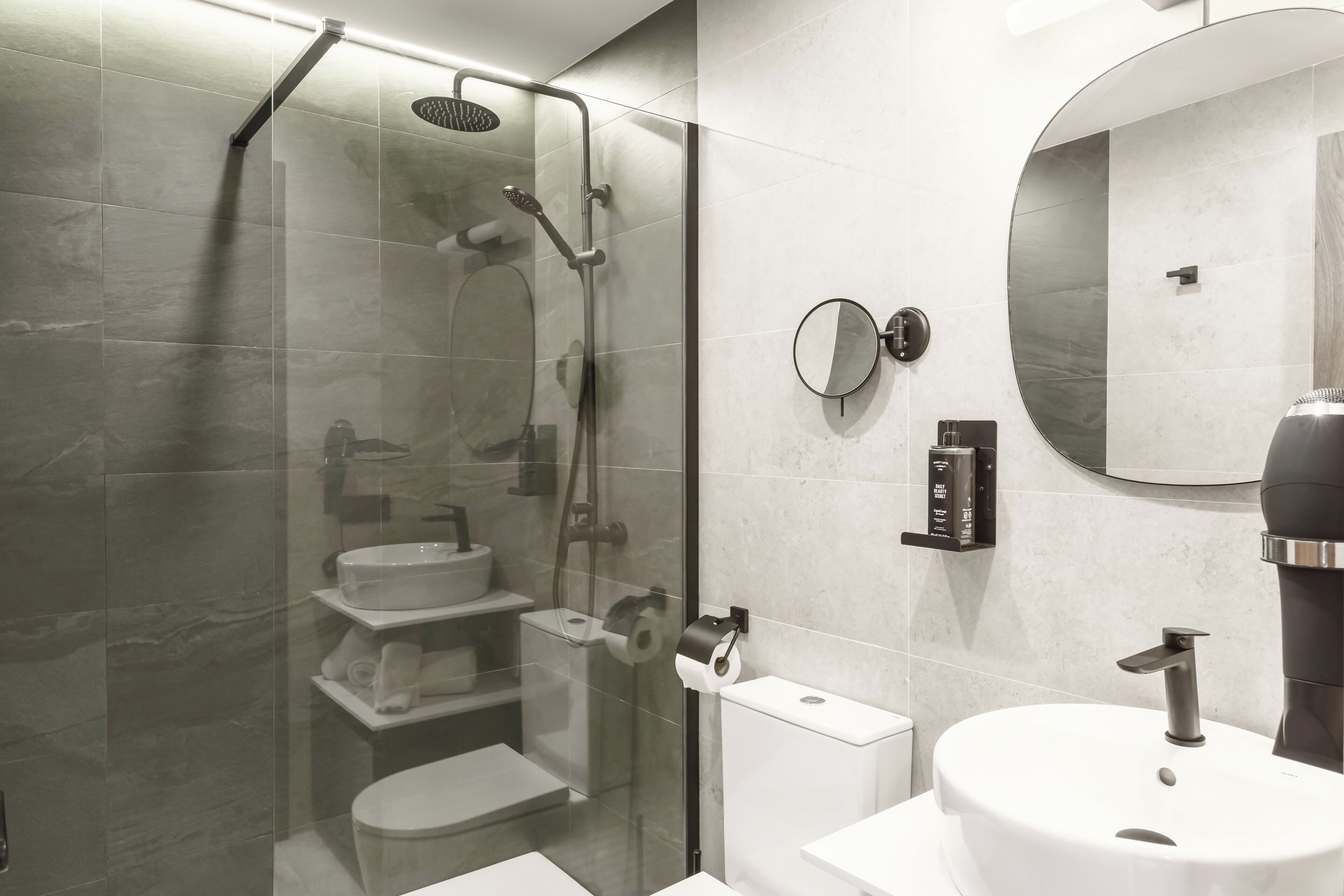 Un baño moderno con ducha acristalada, inodoro, lavabo y espejo.
