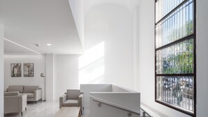 Una habitación moderna y minimalista con un ventanal grande, un sofá, una silla y una mesita de centro.