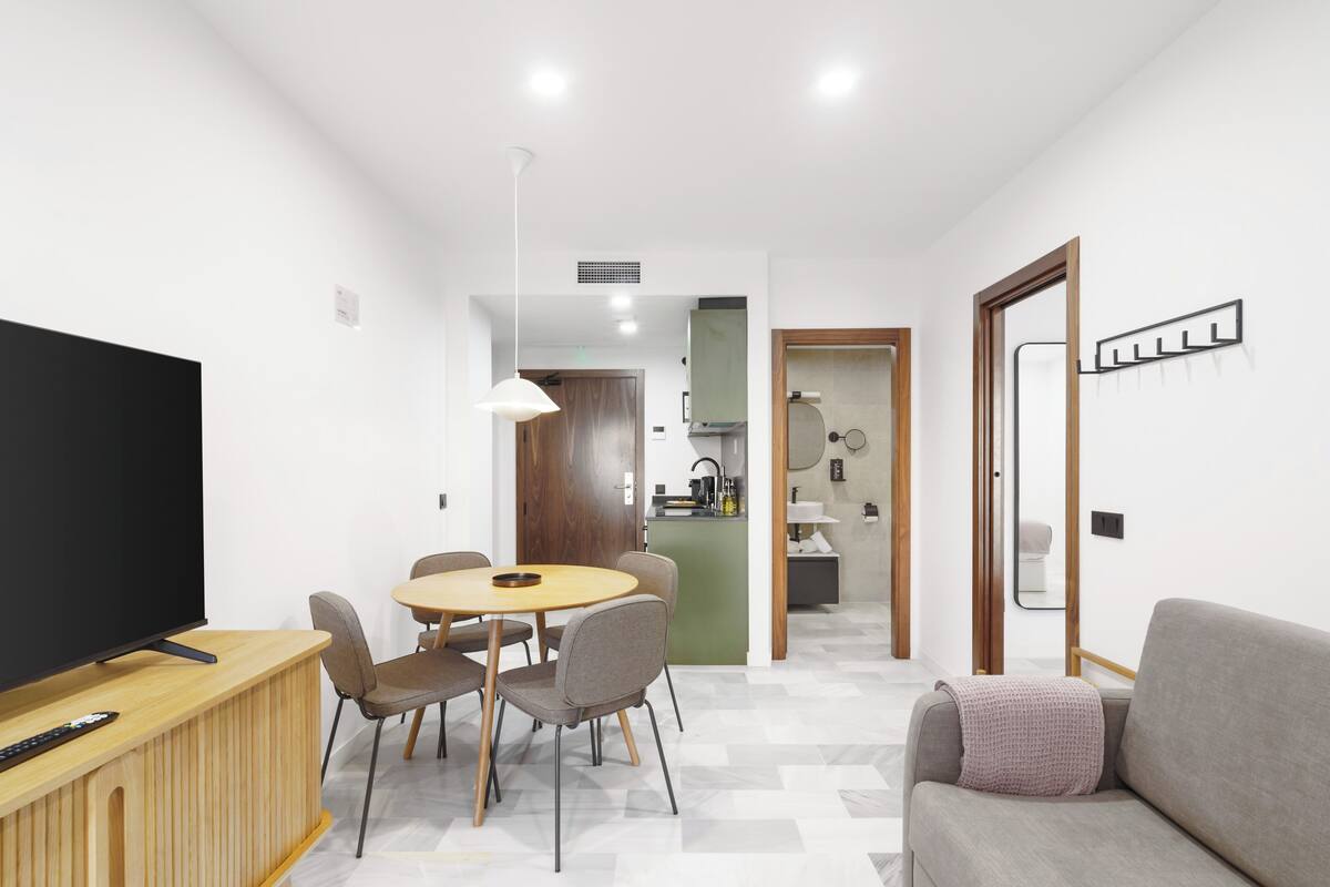 Una sala de estar moderna con televisor, mesa de comedor, sillas y sofá.