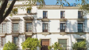 Un edificio de varios pisos con un estilo arquitectónico tradicional, que presenta balcones con barandillas de metal y una entrada central con puerta de madera.