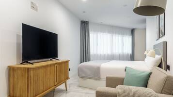 Een moderne hotelkamer met een groot bed, een flatscreen televisie op een houten kast, een bureau en een comfortabele zithoek.