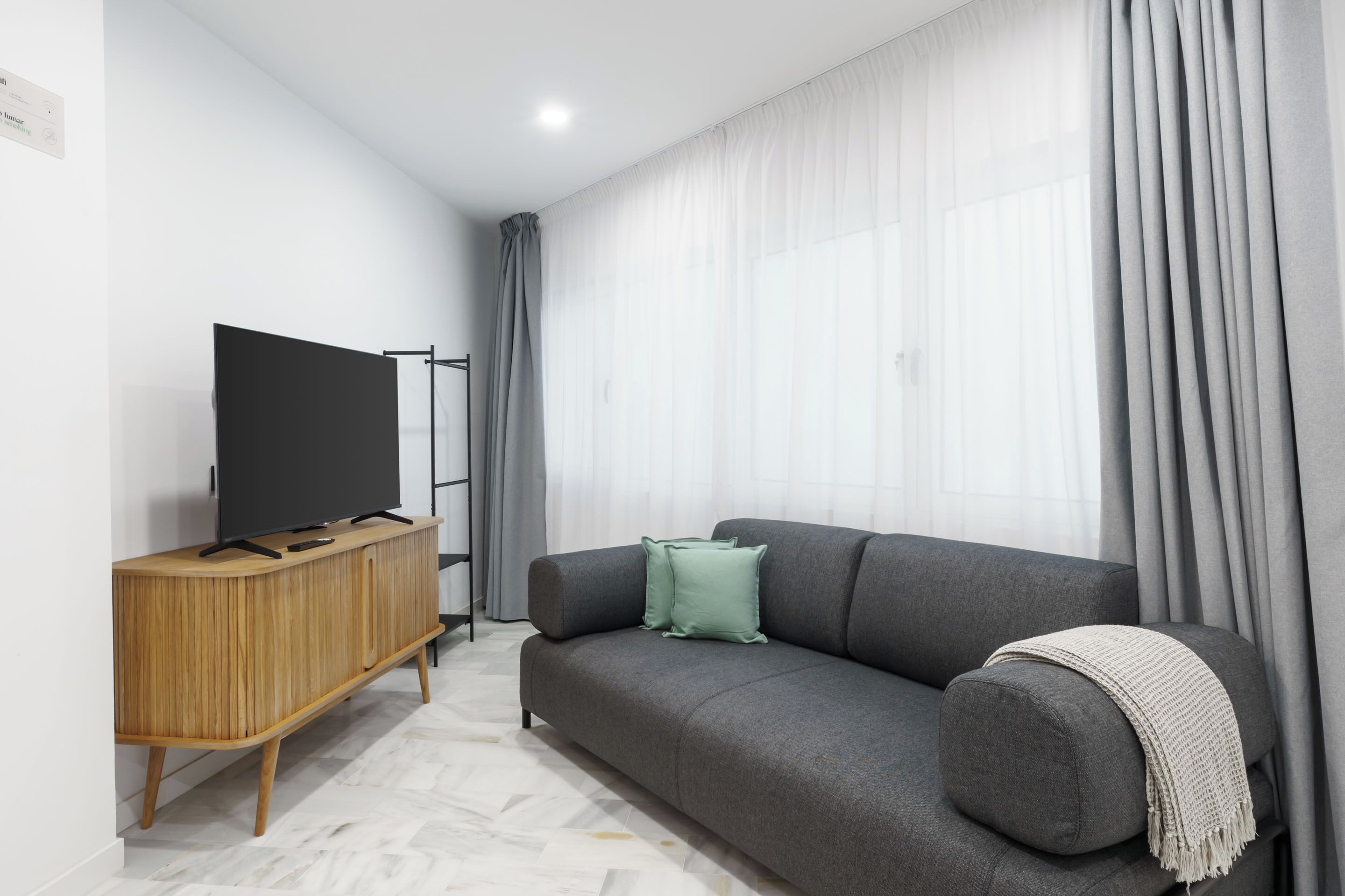 Una sala de estar moderna con un sofá gris, un mueble de madera y un televisor de pantalla plana.