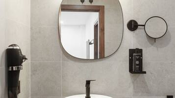 A modern bathroom with a round mirror, a white sink, and a towel rack.