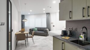 Una habitación de hotel moderna con kitchenette, zona de comedor y sala de estar.