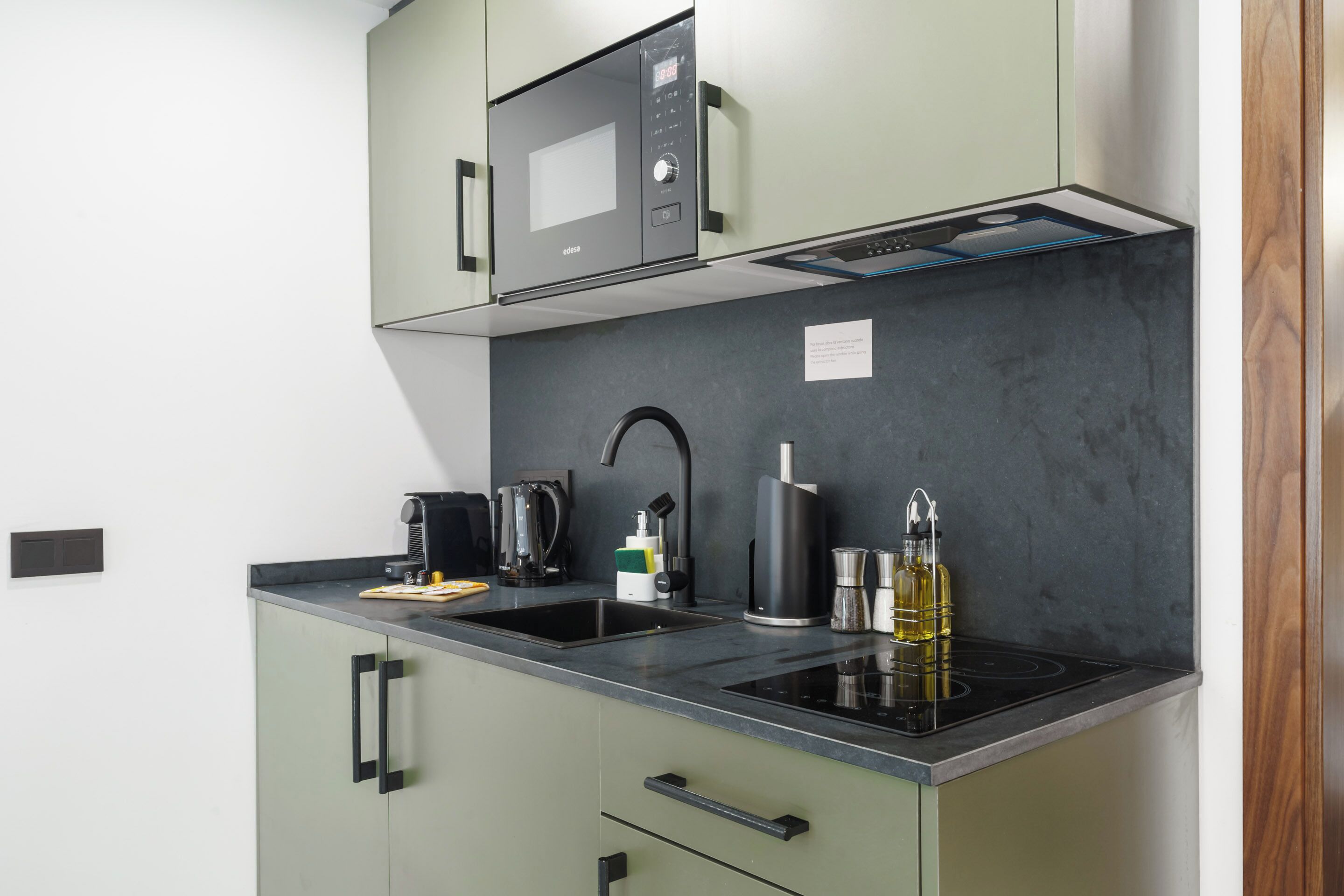 Una cocina compacta equipada con microondas, hervidor y cafetera.