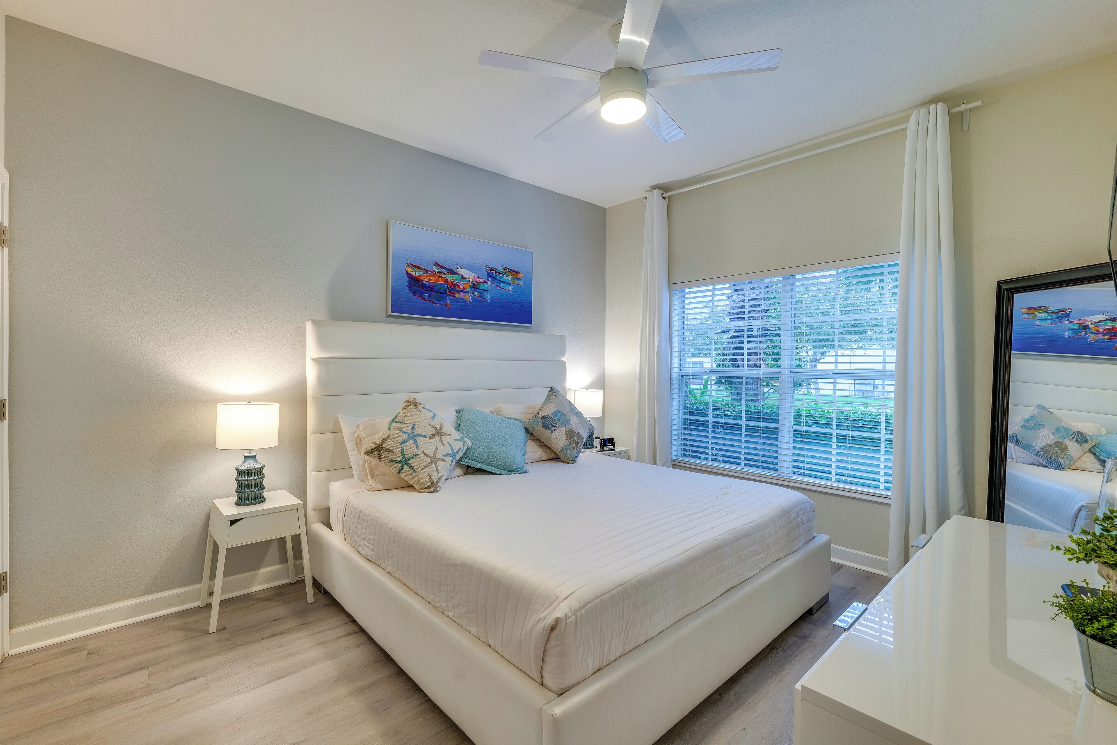 A bedroom with a bed, bedside table, lamp, and a ceiling fan.