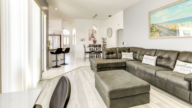 Ein modernes Wohnzimmer mit einem Ecksofa, einem Essbereich und einer Küche im Hintergrund.
