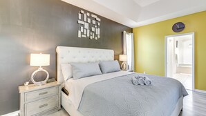 Ein Schlafzimmer mit Bett, Nachttischen, einer Wanduhr und einer Tür.