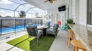 Eine sonnendurchflutete Terrasse mit Pool, Sitzgelegenheit und Deckenventilator.