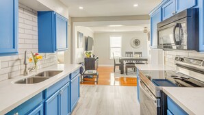 A modern kitchen with blue cabinets, stainless steel appliances, and a dining area with a wooden table and chairs. - 1 Mi to Dtwn: Home w/ Furnished Patio in Pensacola (Pensacola)